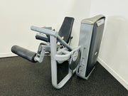 A commercial seated leg curl machine with gray upholstery and a black weight stack, designed for strength training.